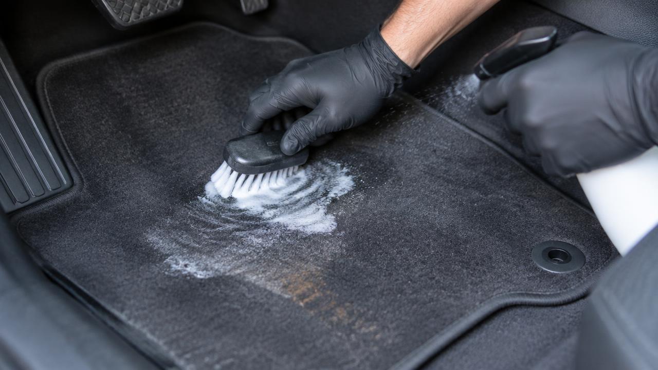 Detailer brushing out a stain on a car floor mat